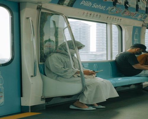 Person holding a smartphone while sitting on a commuter train in Jakarta